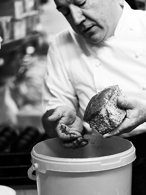Arnaud Delmontel ajoutant des graines de pavot en décoration sur un cake citron-pavot, artisan boulanger pâtissier à Paris